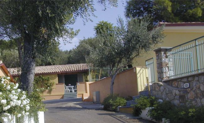 Entrata di una casa gialla con un cortile e sedie all'aperto.