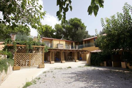 Complesso residenziale con terrazze e rampicanti. Circondato da alberi.