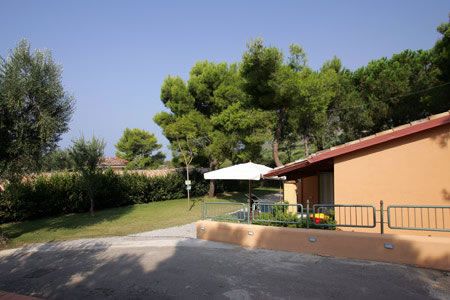 Edificio singolo con ombrellone bianco su una piccola terrazza. Alberi intorno.