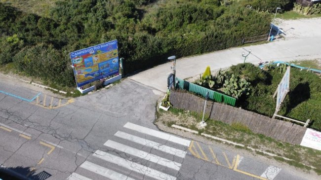 Ingresso di un campeggio con cartellone e strada.
