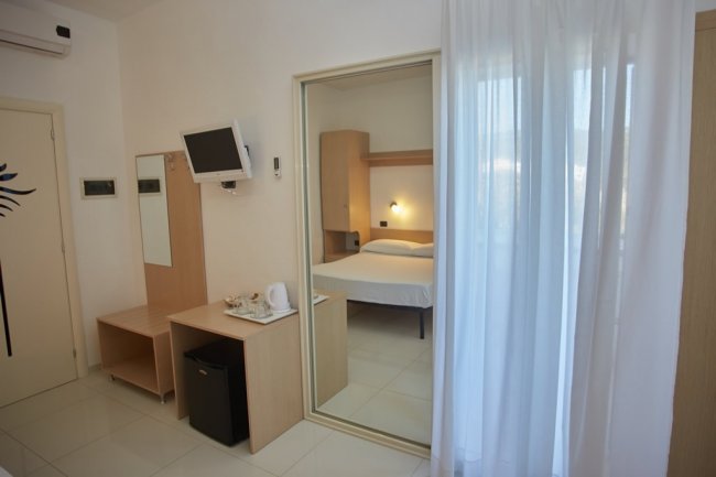 Camera d'hotel con specchio e TV.