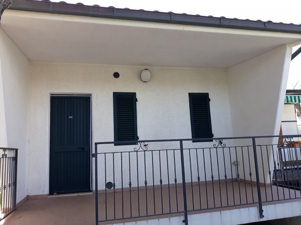 Veranda con porta e finestre verdi.