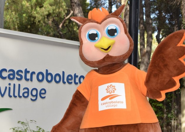 Mascotte gufo sorridente con cartello Castroboleto Village.