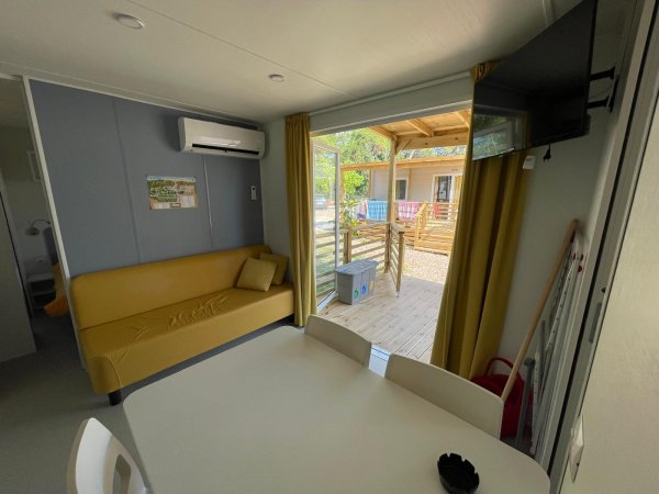 Interno con divano giallo, tavolo bianco e vista su terrazza.