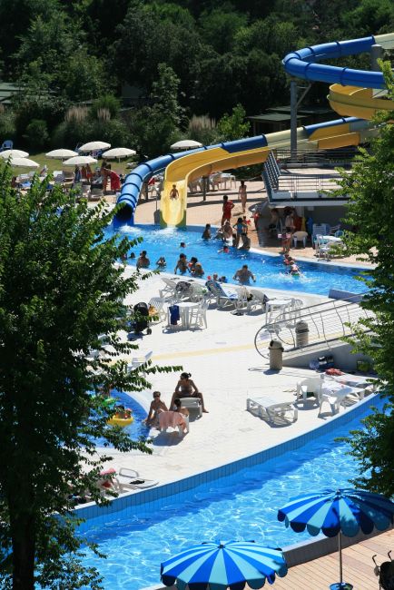 Parco acquatico con scivoli e piscina affollata.