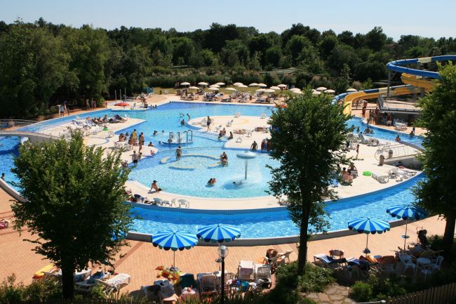 Piscina con molte persone e ombrelloni.