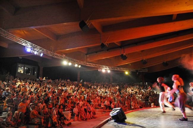 Esibizione sul palco con folla spettatrice.