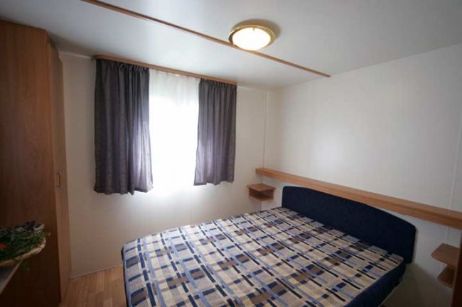 Una camera da letto con un letto matrimoniale, tende scure e arredamento minimalista.