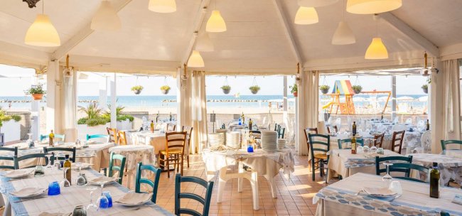 Ristorante vista mare con tavoli apparecchiati.
