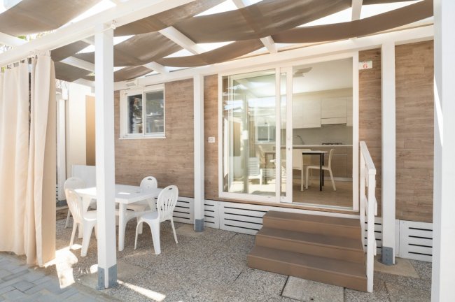 Terrazza con tavolo e sedie di plastica bianca.