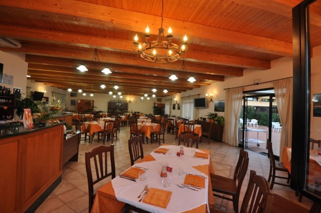 Interno di ristorante con tavoli apparecchiati e soffitto in legno.