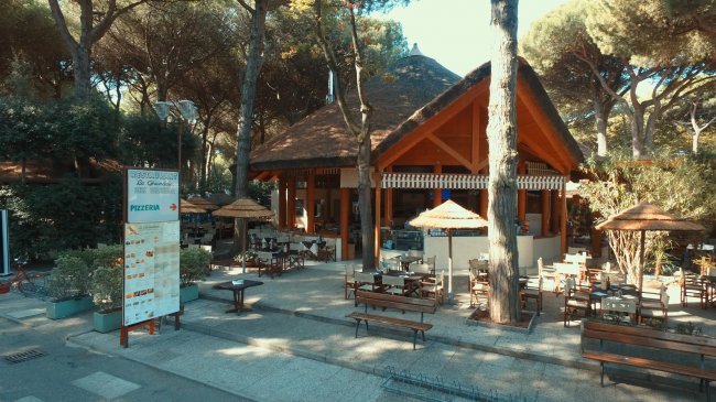 Ristorante all'aperto con tavoli sotto gli alberi.