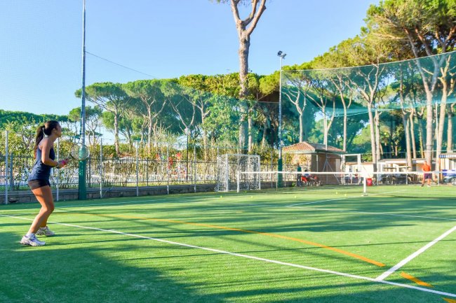 Donna gioca a tennis su un campo all'aperto.