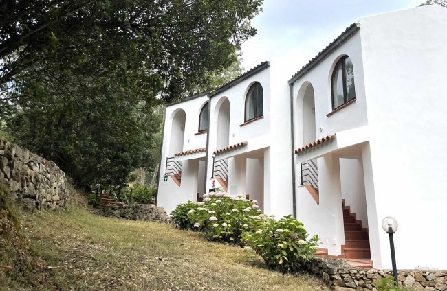 Edifici bianchi con scale esterne e giardino.