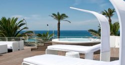 Terrazza con lettini bianchi, vasca idromassaggio e vista mare.