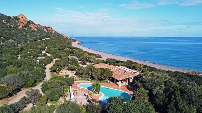Complesso con piscina vicino alla costa e colline.