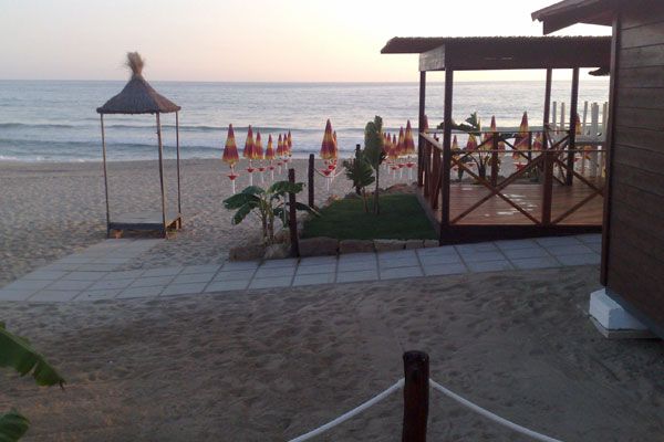 Spiaggia al tramonto con ombrelloni chiusi.