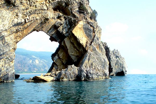 Una formazione rocciosa con un grande arco sopra il mare.