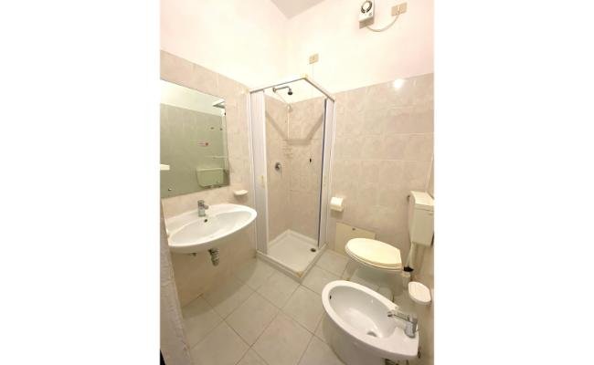 Bagno con doccia, lavabo, bidet e WC. Rivestimento chiaro.