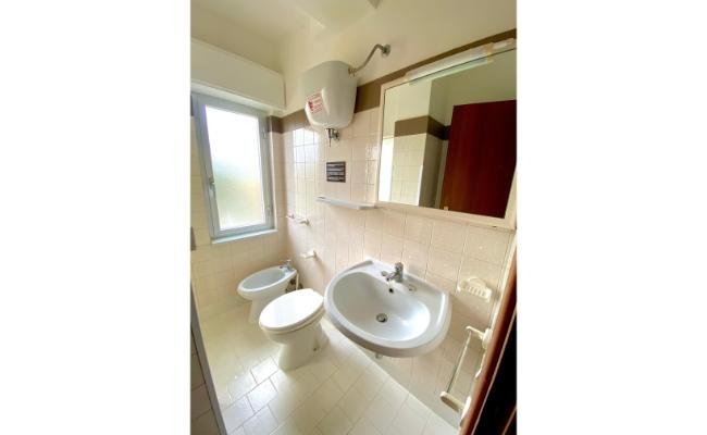 Bagno con lavabo, bidet e WC. Finestra laterale e specchio sopra il lavandino.