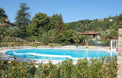 Piscina all'aperto circondata da sedie a sdraio e vegetazione.