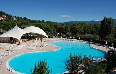 Una piscina con sedie a sdraio e grandi tendoni bianchi.