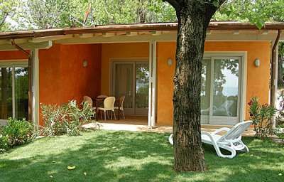Patio con sedie, prato verde e alberi.