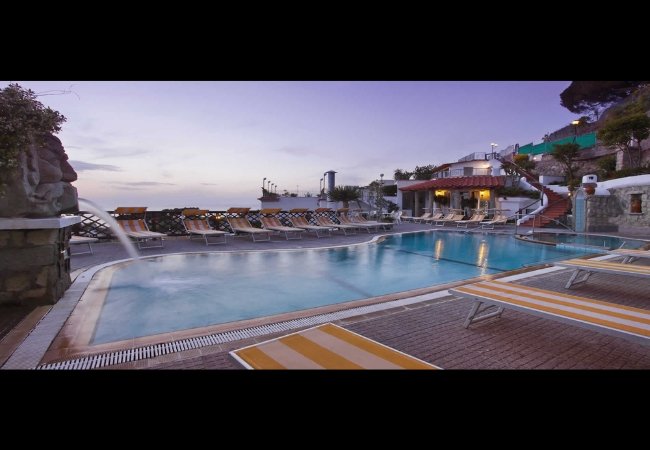 Piscina all'aperto con lettini al tramonto.