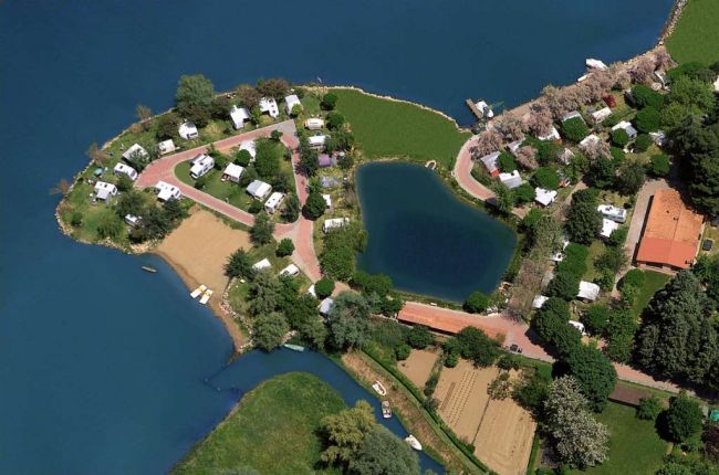 Vista dall'alto di una penisola con roulotte e un piccolo laghetto circondato dall'acqua.