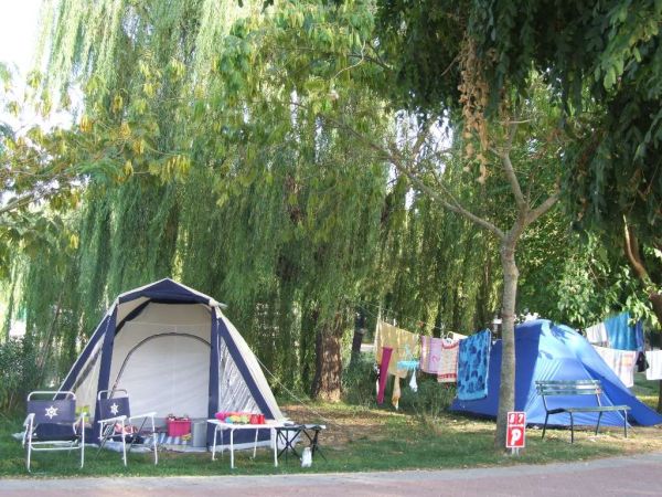 Campeggio con due tende, sedie pieghevoli e panni stesi tra gli alberi.
