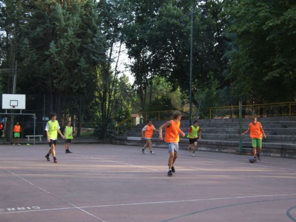 Partita di calcio con ragazzi che indossano casacche arancioni e verdi su un campo all'aperto.