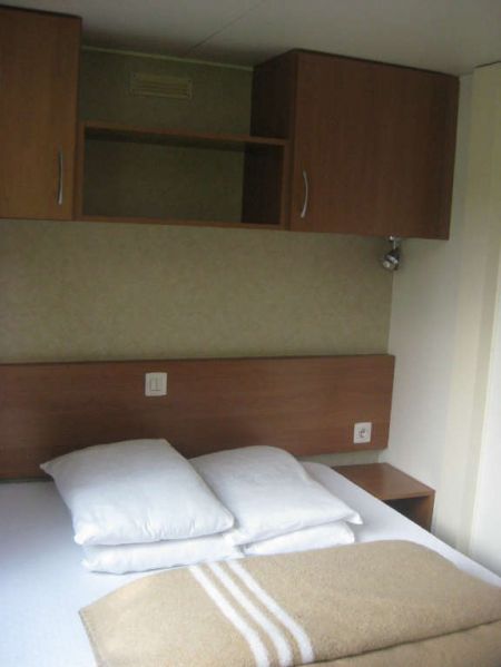 Camera da letto con letto matrimoniale, cuscini e armadietti in legno.