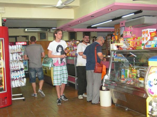 Interno di un minimarket con clienti che fanno acquisti.