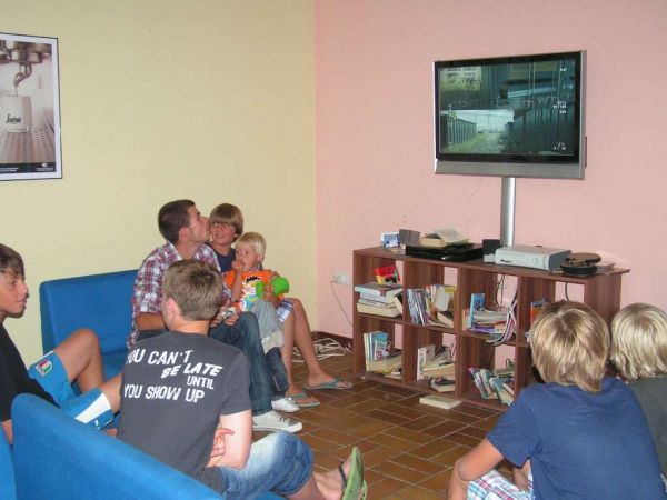 Gruppo di ragazzi in un salotto guarda la TV.