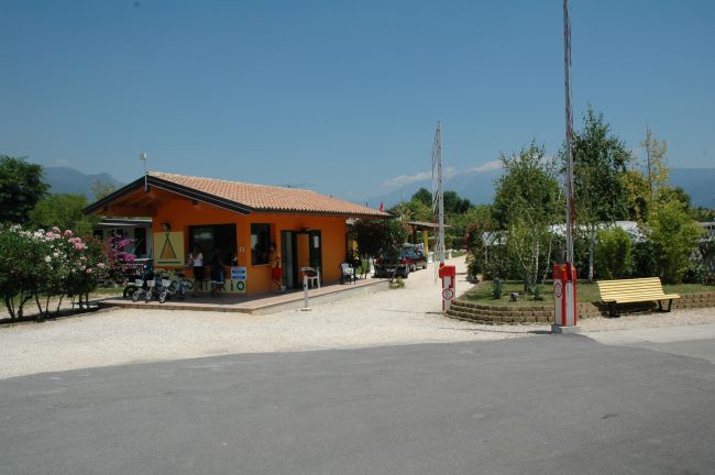 Edificio arancione con giardino e panchine, cielo sereno e alberi intorno.