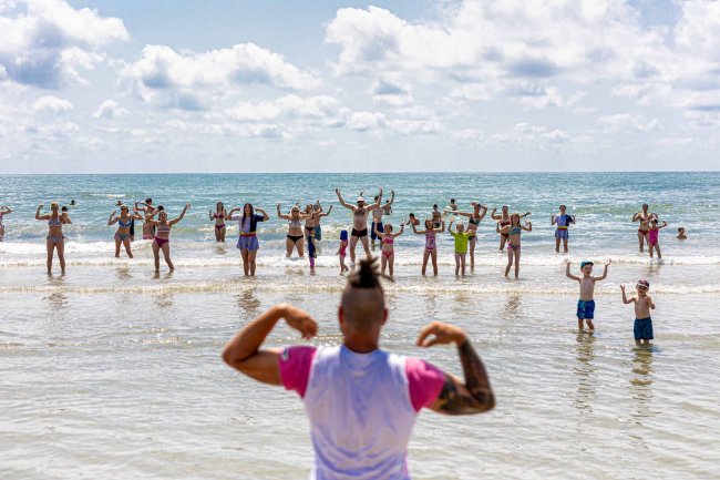 Persone fanno esercizi in mare sotto il sole.