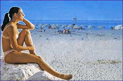 Una donna seduta su uno scoglio guarda il mare; ombrelloni chiusi sulla spiaggia.